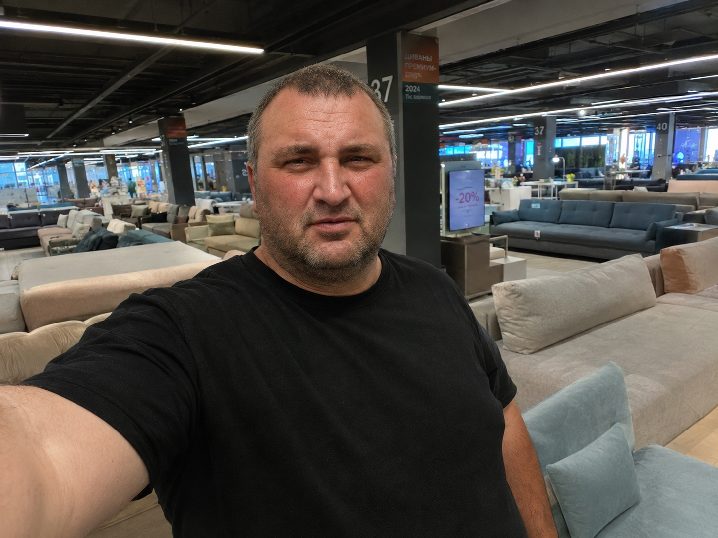 Мужчина стоит в мебельном магазине на фоне диванов