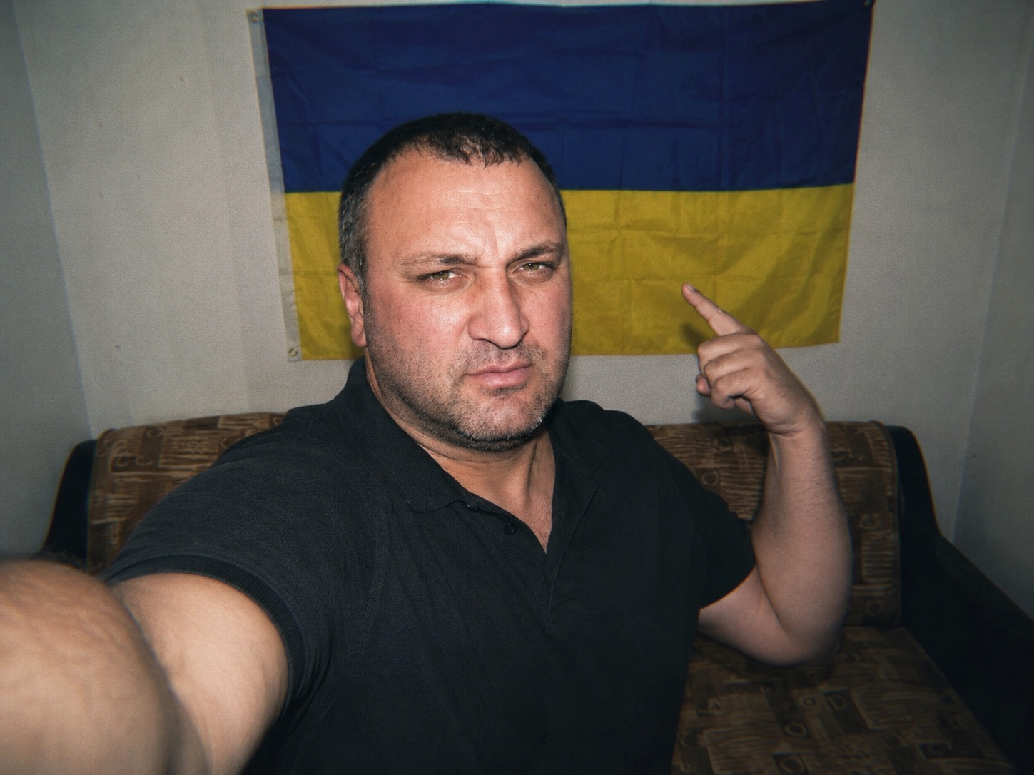 Адом Авенян на фоне украинского флага как символ антивоенной позиции против войны