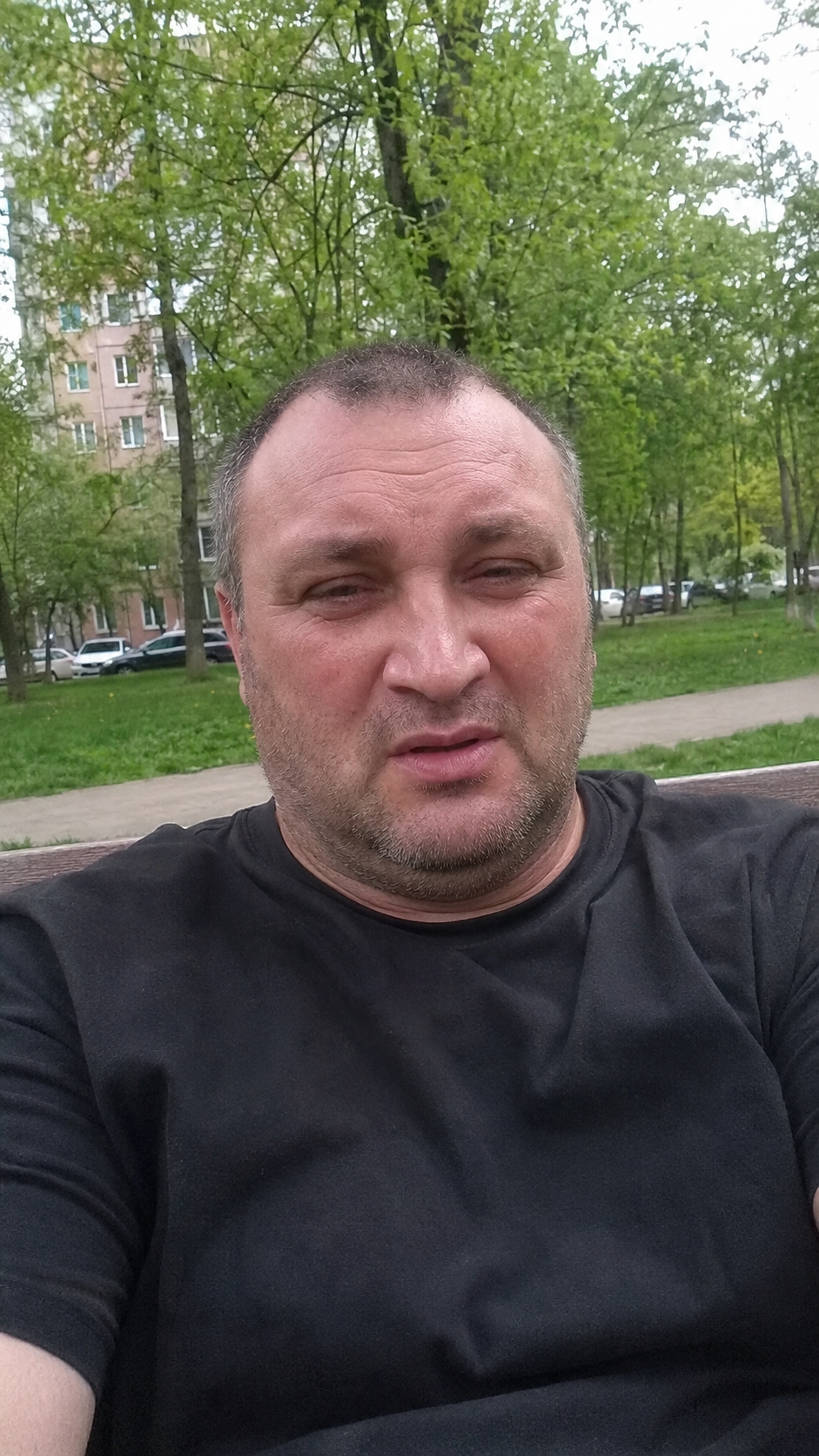 Уставший мужчина сидит на лавке в московском дворе и говорит о зависимости